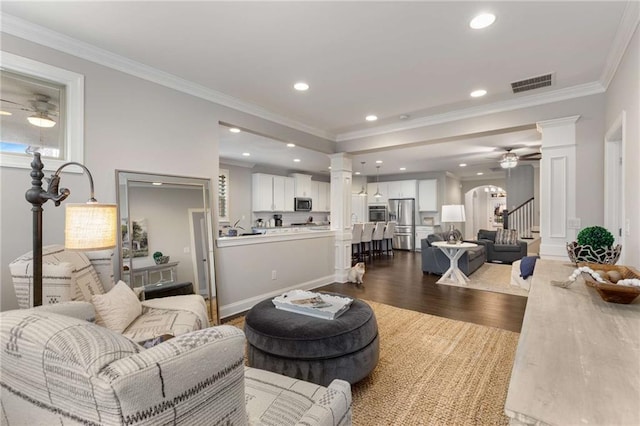 living room featuring dark wood-style floors, visible vents, decorative columns, and a ceiling fan