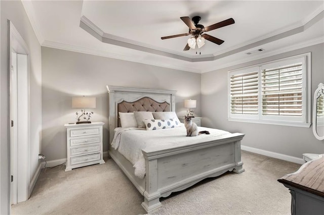 bedroom featuring ornamental molding, a tray ceiling, light carpet, and baseboards