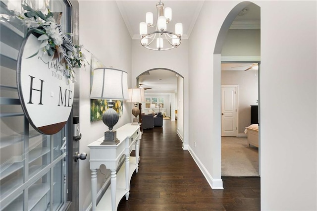 entryway with arched walkways, baseboards, dark wood-style floors, and crown molding