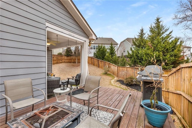 deck with a fenced backyard, a fire pit, and area for grilling