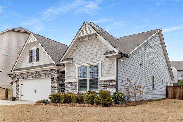 view of front of property featuring stone siding, driveway, an attached garage, and fence