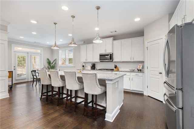 kitchen with appliances with stainless steel finishes, dark wood-style flooring, backsplash, and white cabinetry