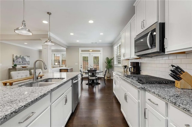 kitchen featuring stainless steel appliances, a sink, ornamental molding, dark wood-style floors, and tasteful backsplash