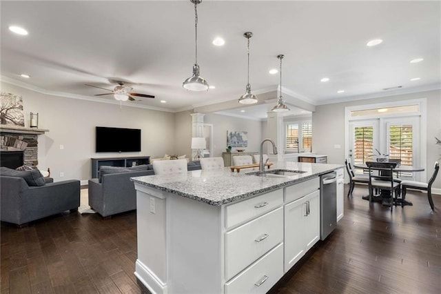 kitchen featuring dark wood-style flooring, a center island with sink, open floor plan, a sink, and a stone fireplace