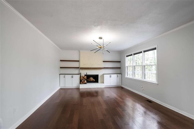 unfurnished living room with dark hardwood / wood-style floors, a notable chandelier, ornamental molding, and a brick fireplace