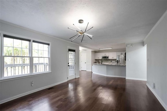 unfurnished living room featuring a textured ceiling, dark hardwood / wood-style floors, ornamental molding, and a notable chandelier