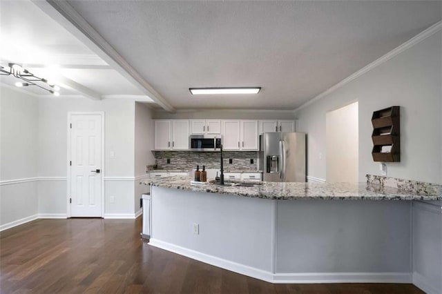 kitchen with light stone countertops, white cabinets, kitchen peninsula, and appliances with stainless steel finishes