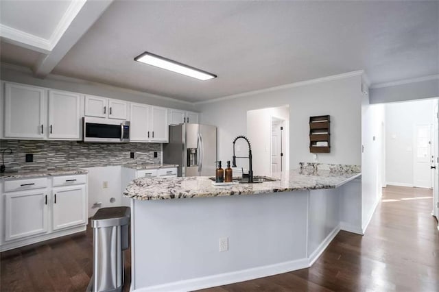 kitchen with kitchen peninsula, stainless steel appliances, light stone countertops, white cabinets, and sink