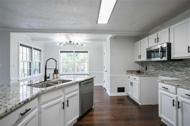 kitchen with stainless steel appliances, beamed ceiling, light stone countertops, white cabinets, and sink