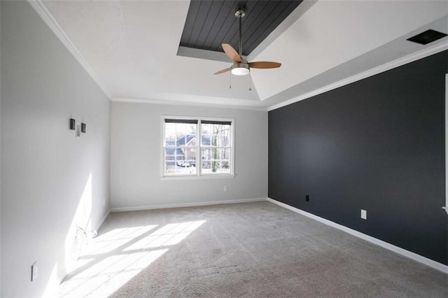 carpeted spare room featuring ceiling fan, ornamental molding, and a tray ceiling