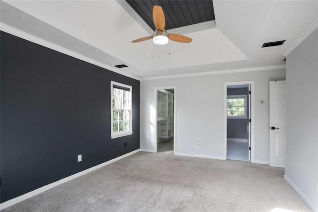 unfurnished bedroom featuring ceiling fan, ensuite bathroom, crown molding, and a tray ceiling