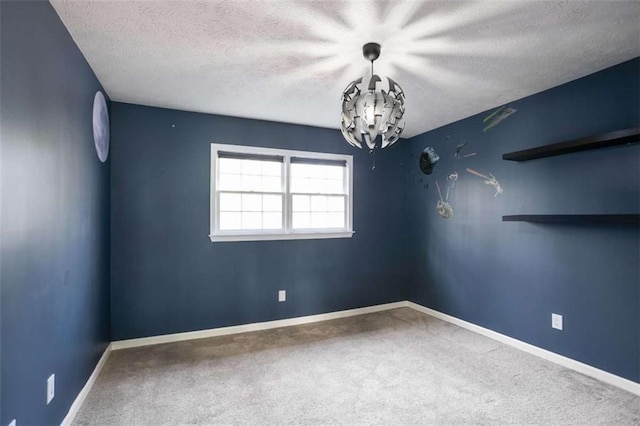 carpeted spare room with a textured ceiling and a chandelier