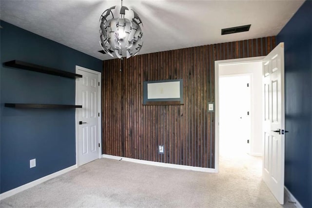 unfurnished room featuring light colored carpet and wood walls