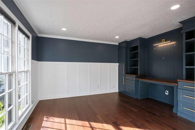 unfurnished office featuring a textured ceiling, crown molding, dark hardwood / wood-style flooring, and built in desk