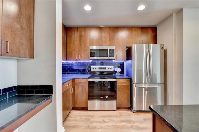 kitchen featuring appliances with stainless steel finishes, brown cabinetry, and tasteful backsplash