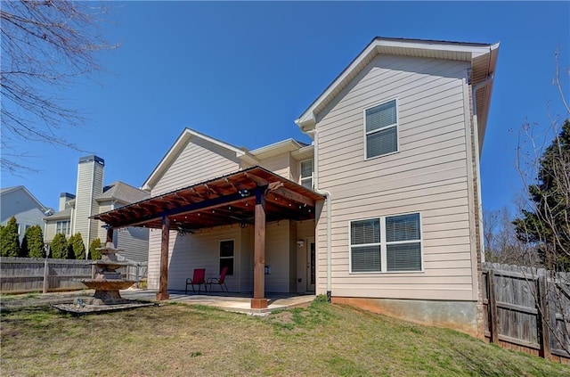 rear view of house featuring a yard, fence, and a patio