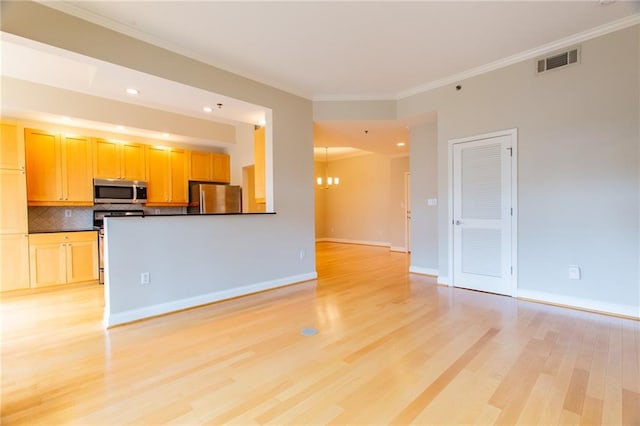 kitchen with crown molding, backsplash, appliances with stainless steel finishes, a notable chandelier, and light hardwood / wood-style floors