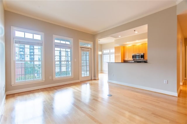 unfurnished living room with ornamental molding, a wealth of natural light, and light hardwood / wood-style floors