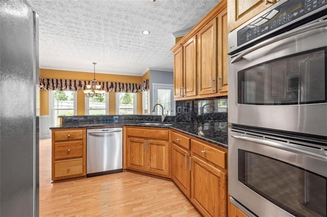 65 Millennial Ct, Lawrenceville, GA 30045 - kitchen with appliances with stainless steel finishes, brown cabinets, light wood-style flooring, a peninsula, and a textured ceiling
