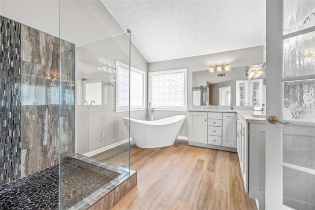 65 Millennial Ct, Lawrenceville, GA 30045 - full bathroom with wood finished floors, tiled shower, a freestanding tub, lofted ceiling, and a textured ceiling