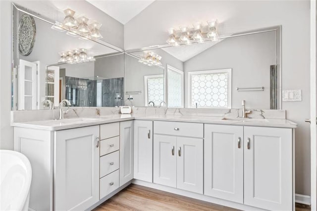 65 Millennial Ct, Lawrenceville, GA 30045 - bathroom with vaulted ceiling, wood finished floors, a soaking tub, and double vanity