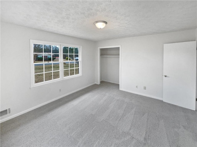 unfurnished bedroom with carpet flooring, a textured ceiling, and a closet