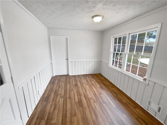 empty room featuring hardwood / wood-style flooring, a healthy amount of sunlight, and a textured ceiling