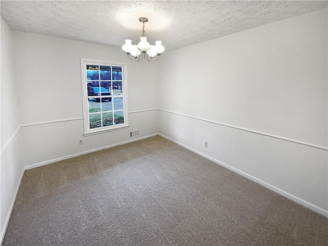 spare room with carpet flooring, a textured ceiling, and a notable chandelier