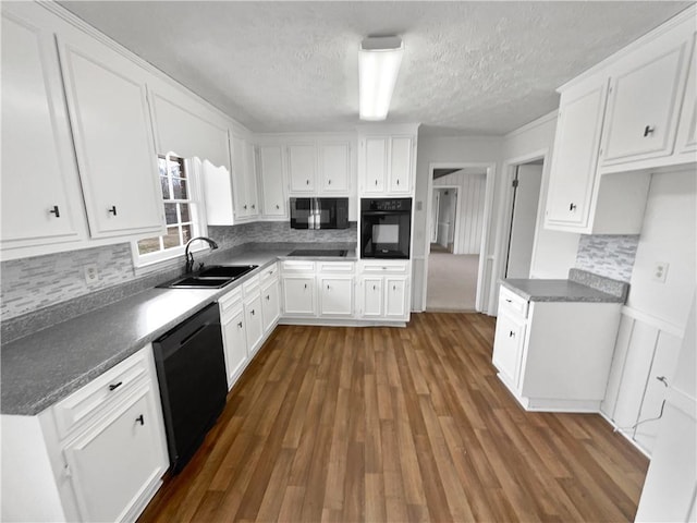 kitchen with dark wood-type flooring, sink, tasteful backsplash, white cabinets, and black appliances