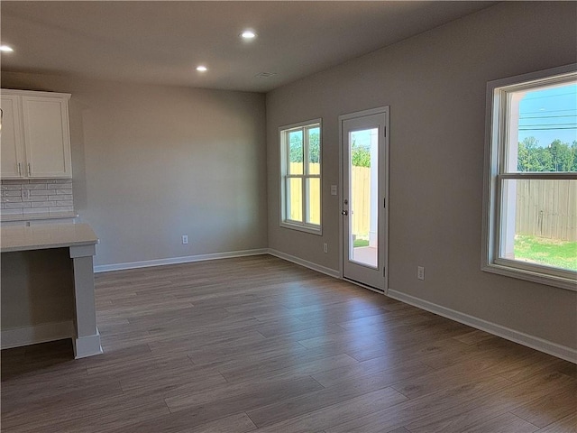 unfurnished living room with dark wood-style floors, a wealth of natural light, and recessed lighting