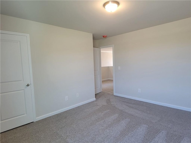 empty room with baseboards and light colored carpet