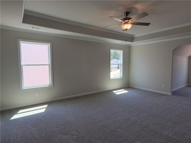 carpeted spare room with arched walkways, a tray ceiling, visible vents, and crown molding