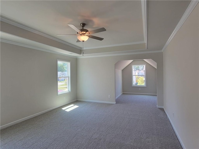 empty room featuring baseboards, a ceiling fan, carpet, a tray ceiling, and crown molding