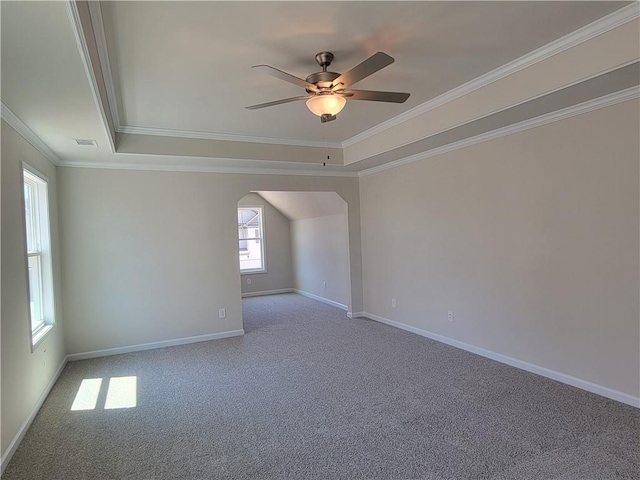 unfurnished room with baseboards, arched walkways, a ceiling fan, ornamental molding, and carpet flooring