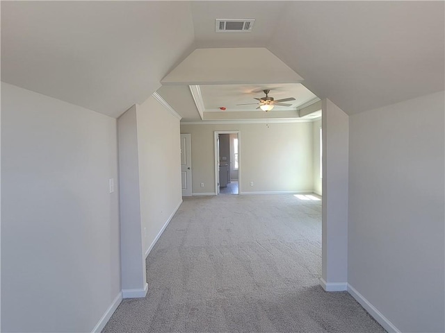 interior space with a tray ceiling, visible vents, light carpet, ceiling fan, and baseboards