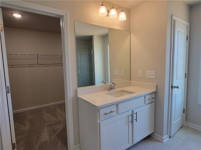 bathroom with baseboards, a spacious closet, and vanity