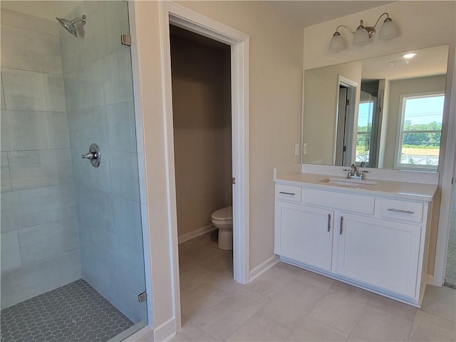 bathroom with toilet, a shower stall, baseboards, and vanity