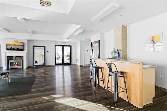 kitchen with a kitchen breakfast bar, kitchen peninsula, dark wood-type flooring, and french doors