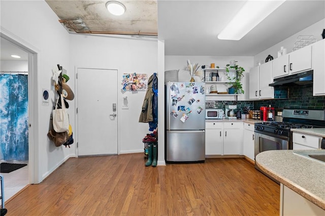 kitchen with decorative backsplash, light wood-type flooring, stainless steel appliances, and white cabinetry