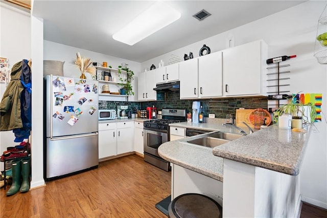 kitchen featuring white cabinets, sink, light hardwood / wood-style flooring, kitchen peninsula, and stainless steel appliances