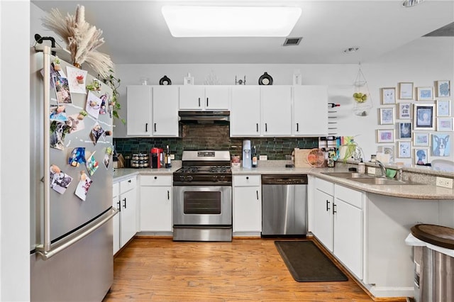 kitchen featuring white cabinets, sink, light hardwood / wood-style flooring, kitchen peninsula, and stainless steel appliances