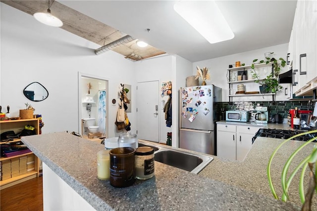 kitchen featuring kitchen peninsula, white cabinetry, dark wood-type flooring, and appliances with stainless steel finishes