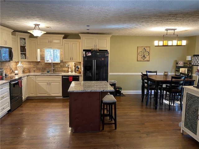 kitchen featuring a kitchen island, pendant lighting, sink, a breakfast bar area, and black appliances