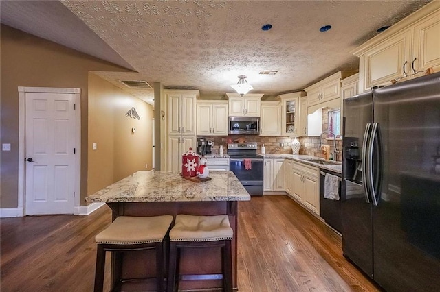 kitchen featuring sink, appliances with stainless steel finishes, dark hardwood / wood-style flooring, a kitchen island, and cream cabinets