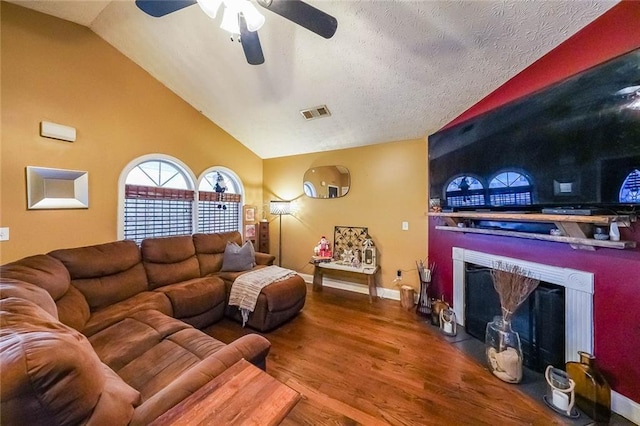 living room with ceiling fan, lofted ceiling, wood-type flooring, and a textured ceiling