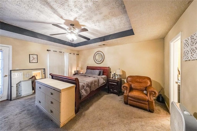 carpeted bedroom with ceiling fan, a textured ceiling, and a tray ceiling