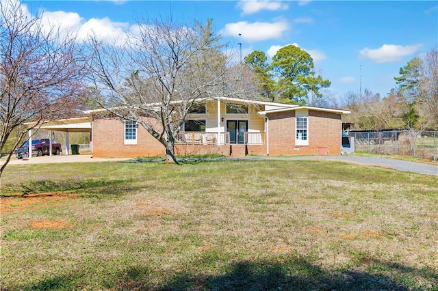 mid-century inspired home featuring brick siding, fence, an attached carport, driveway, and a front lawn