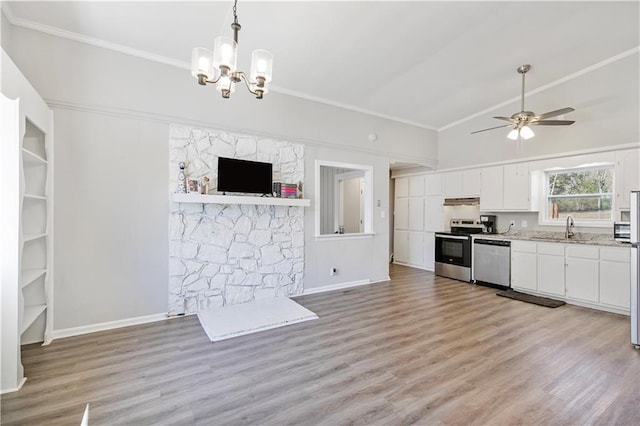 kitchen featuring under cabinet range hood, stainless steel appliances, a sink, white cabinets, and vaulted ceiling