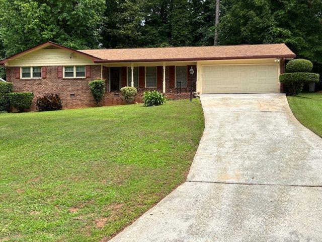 ranch-style house featuring concrete driveway, an attached garage, and a front lawn