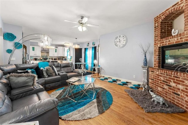 living room with ceiling fan, hardwood / wood-style floors, and a brick fireplace